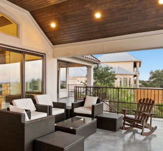 Lujoso patio cubierto con techo con vigas de madera, pisos de baldosas y muebles de mimbre acolchados
