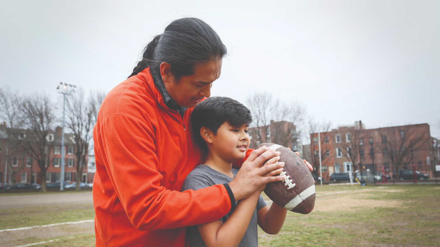 Native American father teaching his son to throw a football