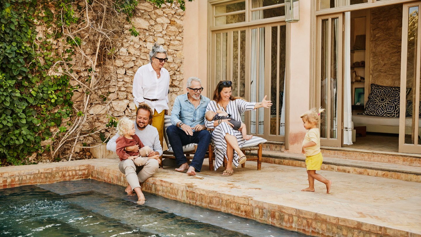 Grandparents, parents and young children enjoying family time at their backyard pool.