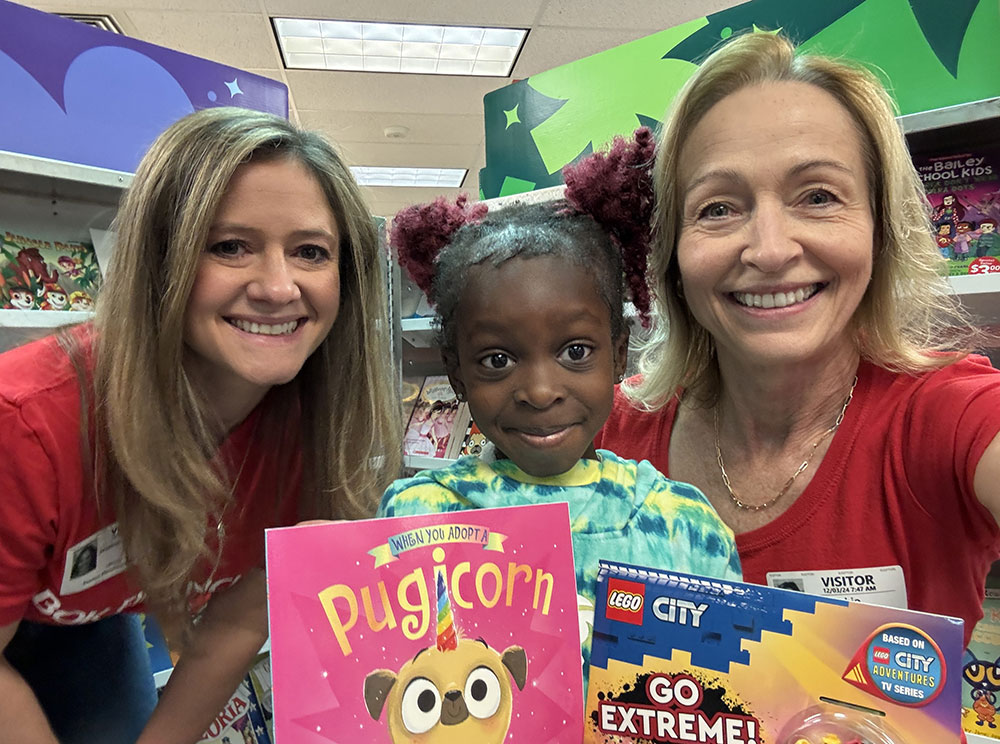 BOKF employees Jessica Johnson (left) and Lorie Rubio (right) help students pick out books in the "If You Give a Child a Book" program in Denver.