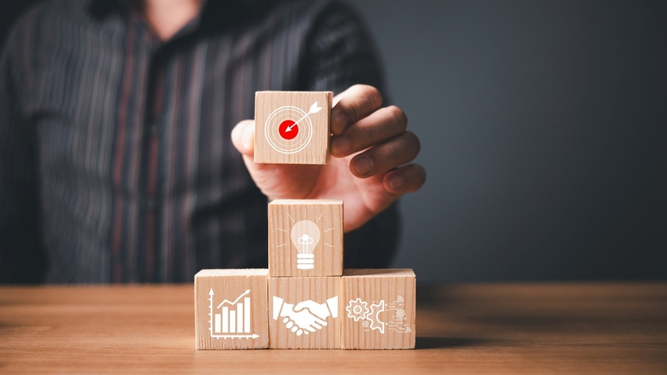 Man stacking wooden blocks placing block with target on top