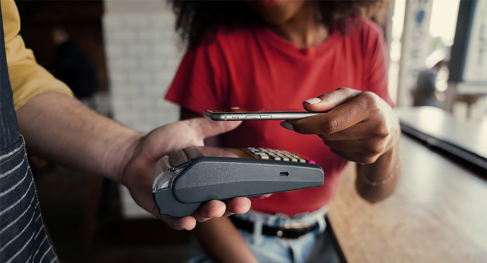 Close up of a young girl using a tap to pay card reader.