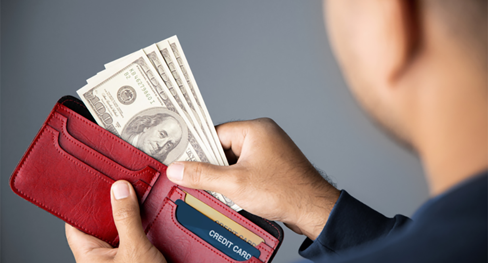 Man pulling a group of bills out of a red wallet.
