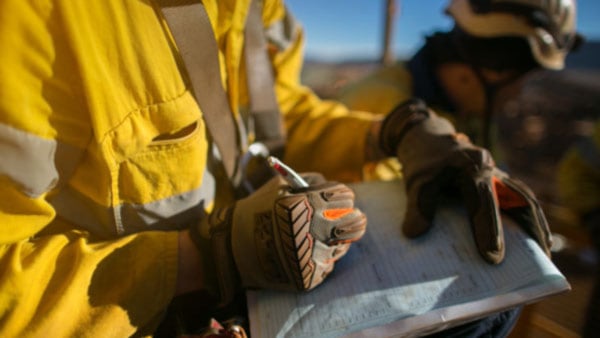 A construction manager fills out a checklist on a clipboard for construction safety compliance.