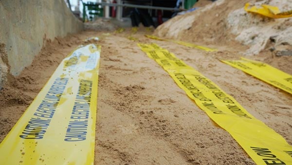 Yellow electrical warning tape on sand alerts of power lines beneath.