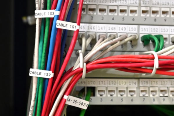 Multiple cables in a data center marked with cable labels.