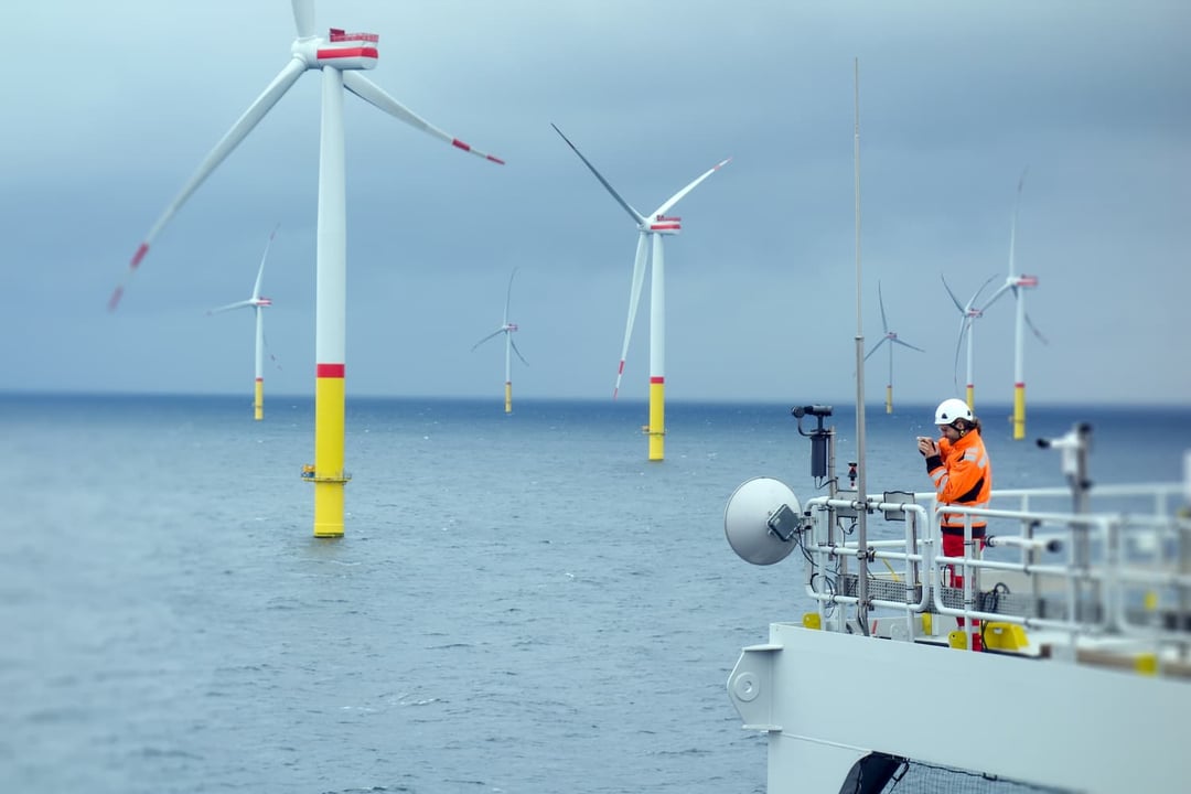 Employee looking at wind mills at sea Employee looking at wind mills at sea