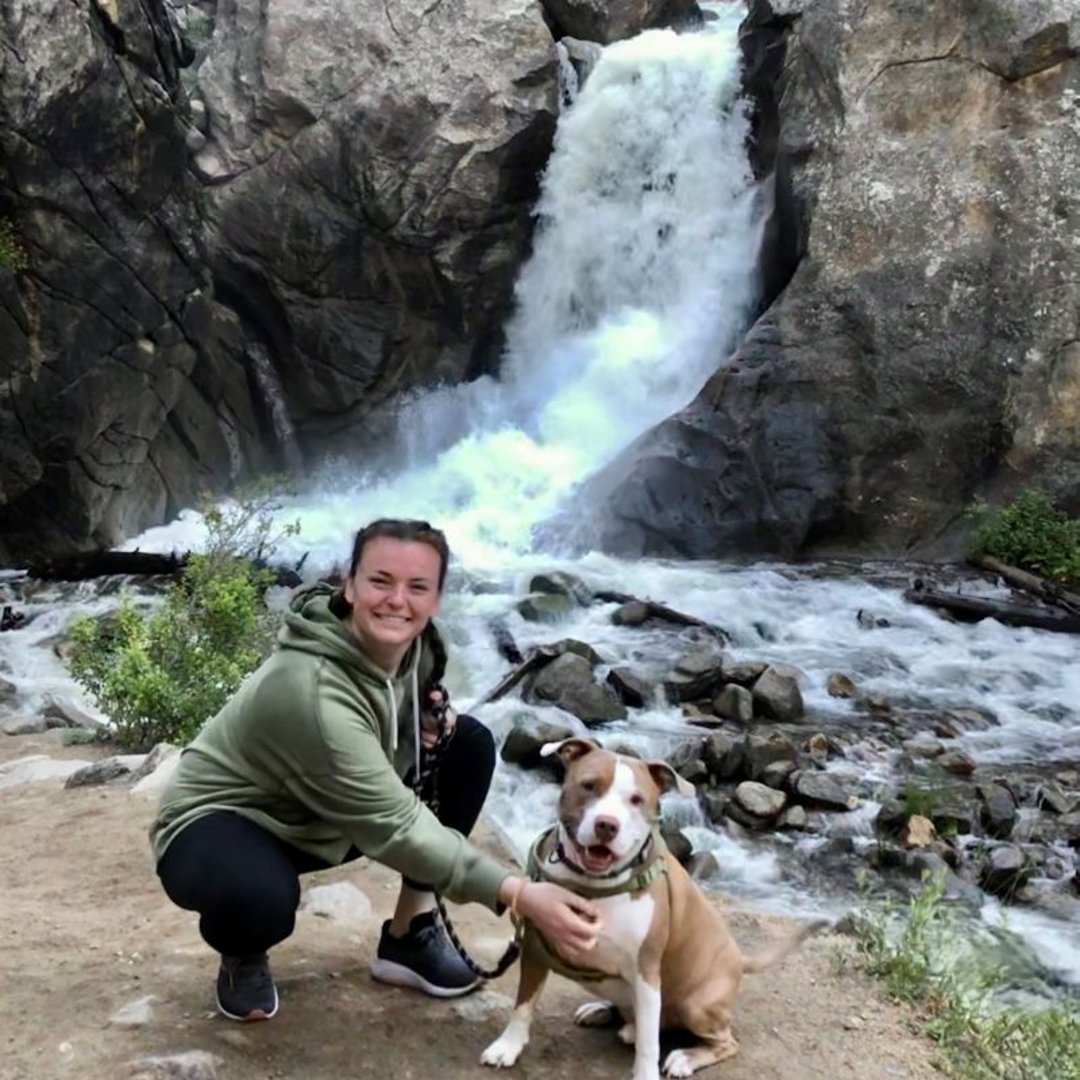 Katie Rossman and her dog Lenny in front of a waterfall