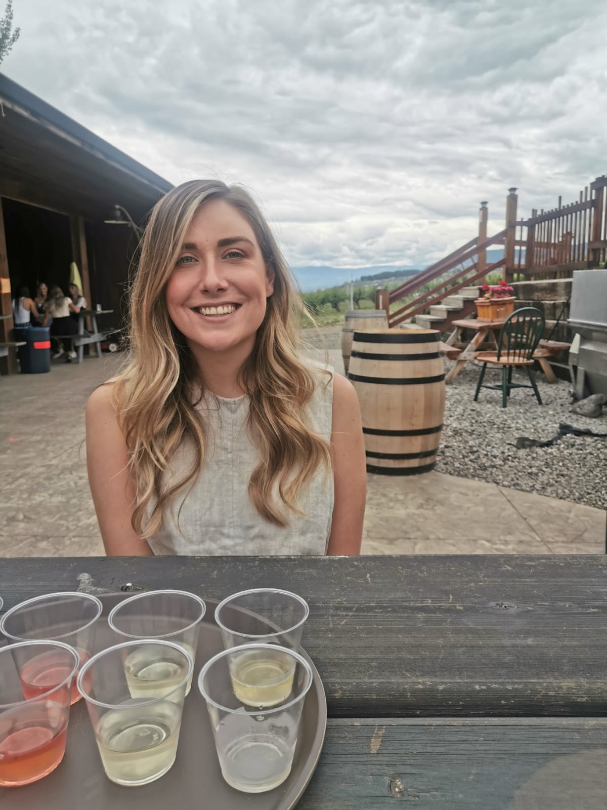 Woman sitting at wooden table with cups of alcohol