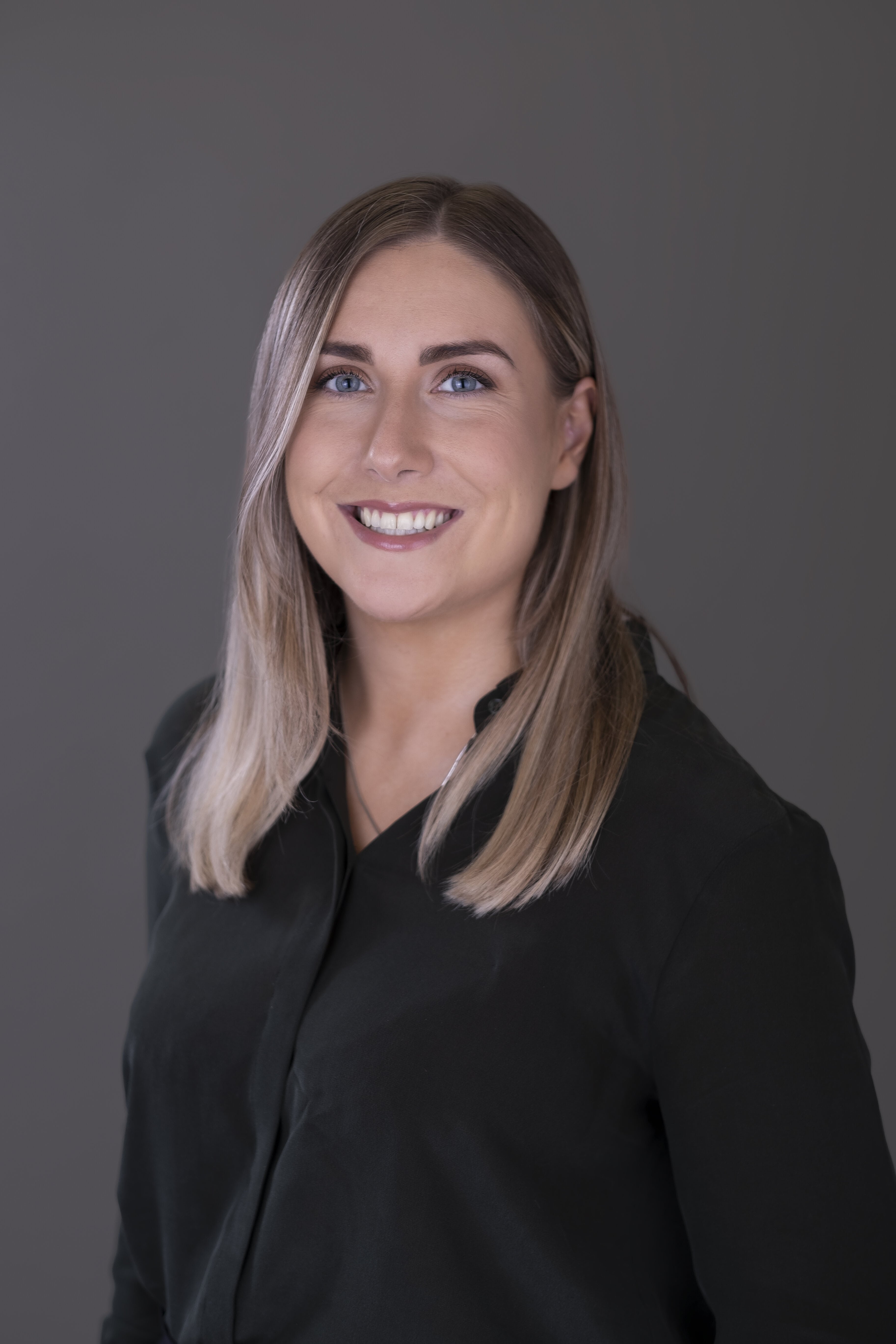 Woman with blonde and brown hair in black dress shirt