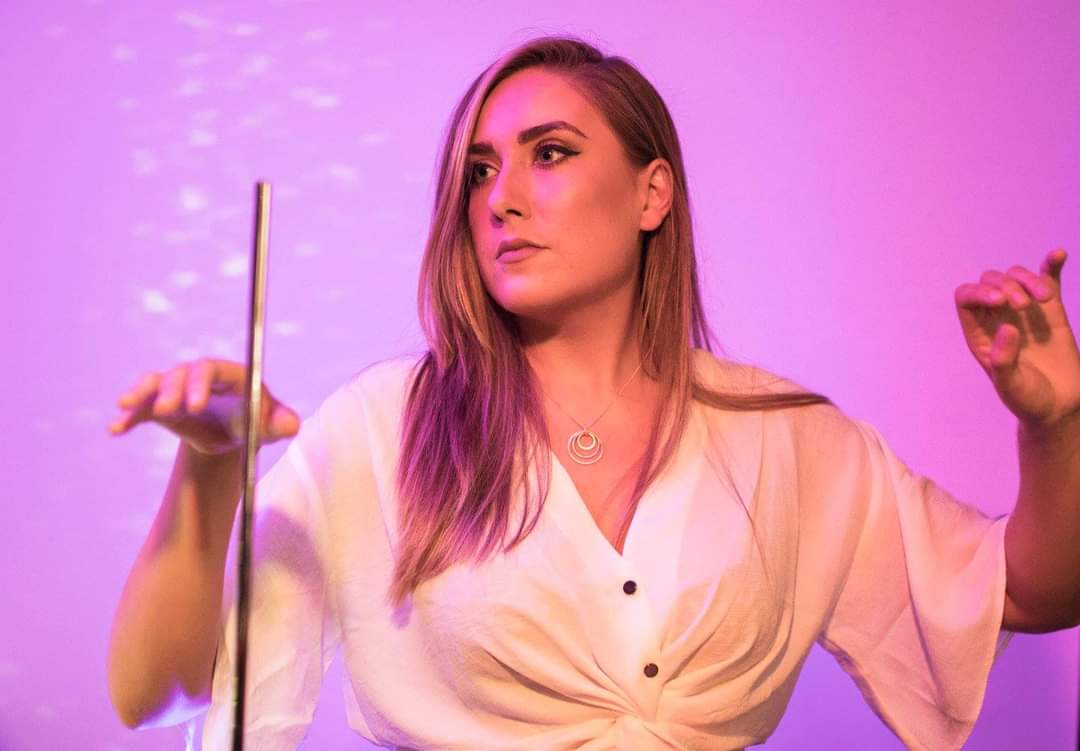 Woman in front of purple wall playing the theremin