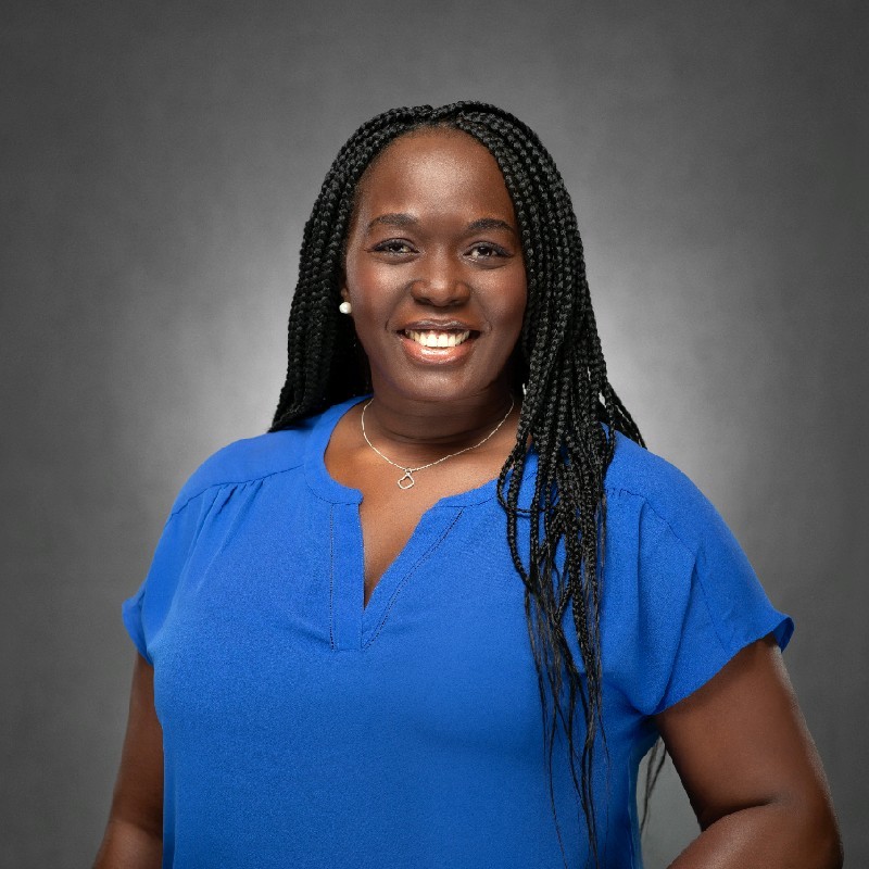 Woman in blue shirt with black hair in front of grey background
