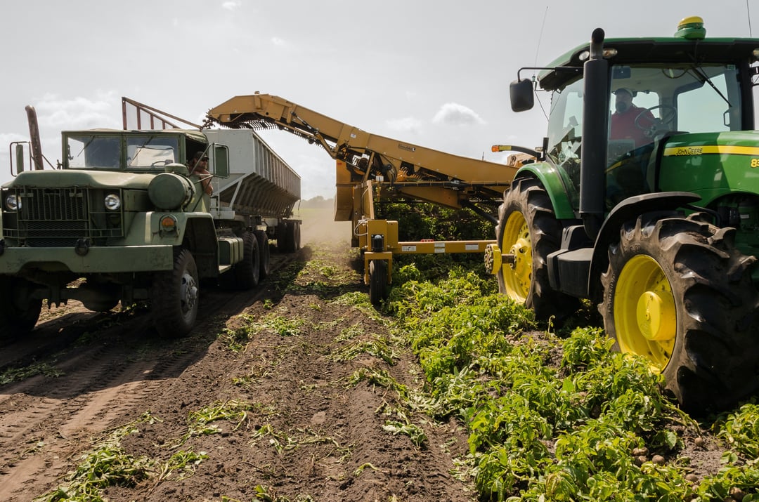 John Deere tractor harvesting crop into truck