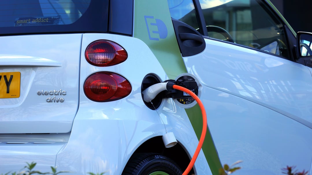 white electric vehicle plugged into charger