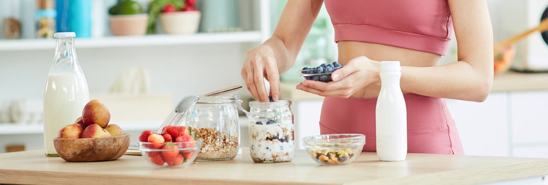 Woman preparing a healthy fruit and oat breakfast in her kitchen after morning exercise