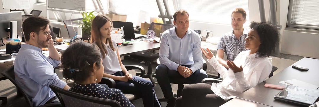 Female boss surrounded by employees speaking casually