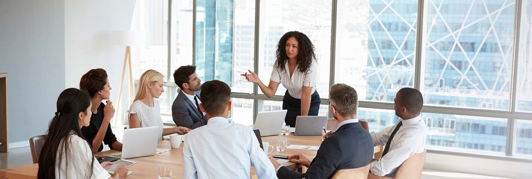 Female boss giving presentation in meeting room with diverse group