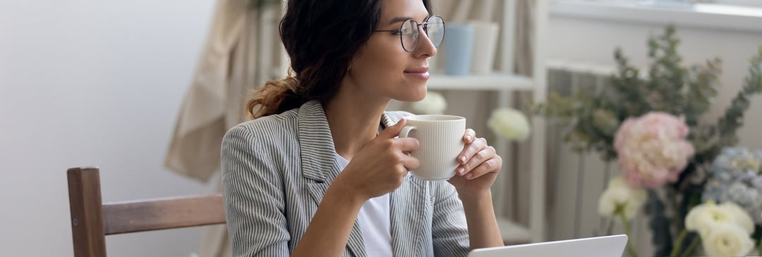 Happy and relaxed employee having coffee at desk