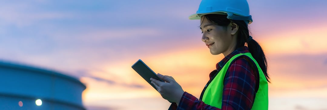 Happy petrochemical worker using tablet at dusk work life balance