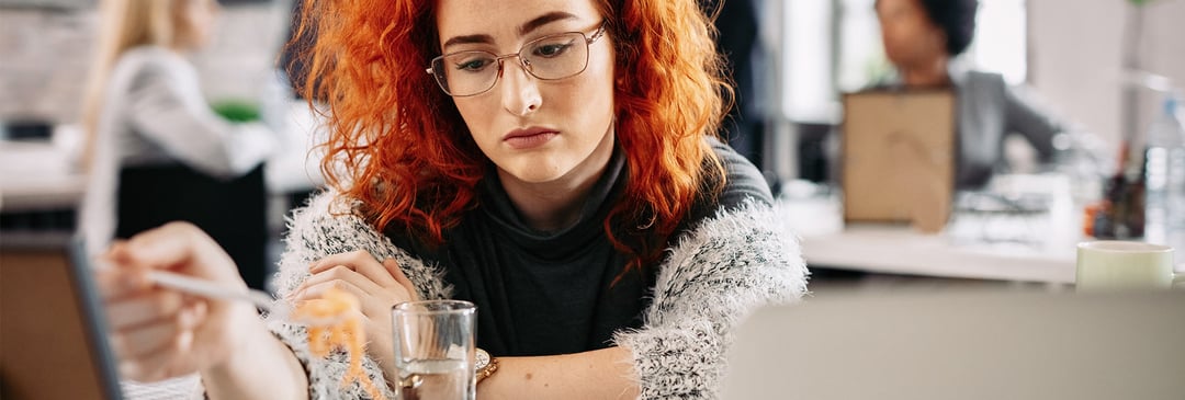 Woman eating lunch alone in the office as a result of tension in the workplace