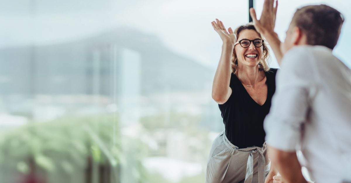Two office workers hi-fiving with joy