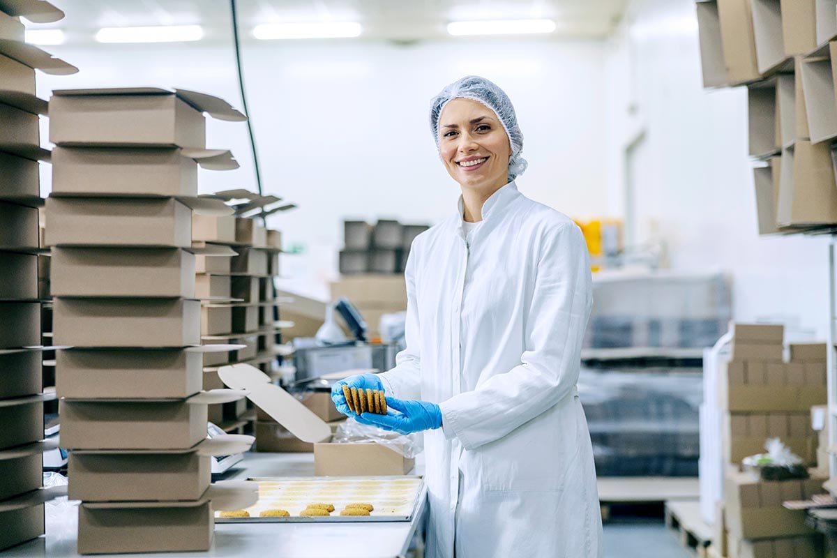 Woman with cookies in food packaging facility