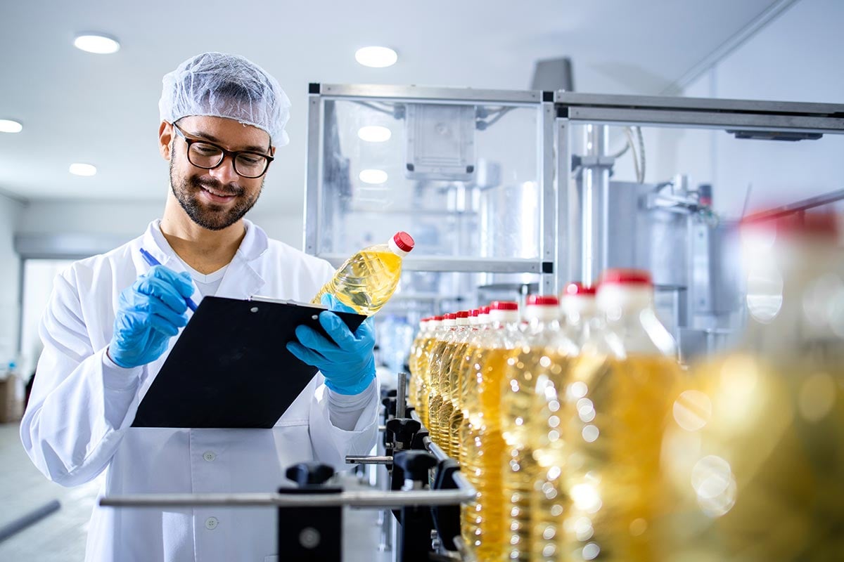 QA worker checks olive oil bottles on production line