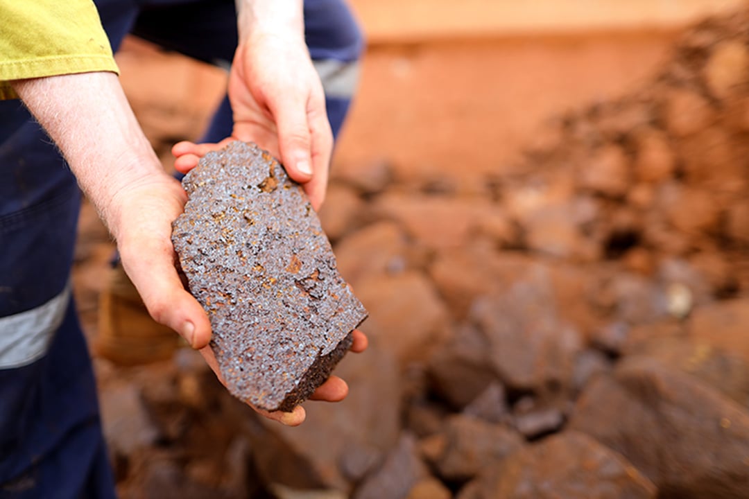 Scientist geologist holding iron ore rock in open field mine site, Perth Australia