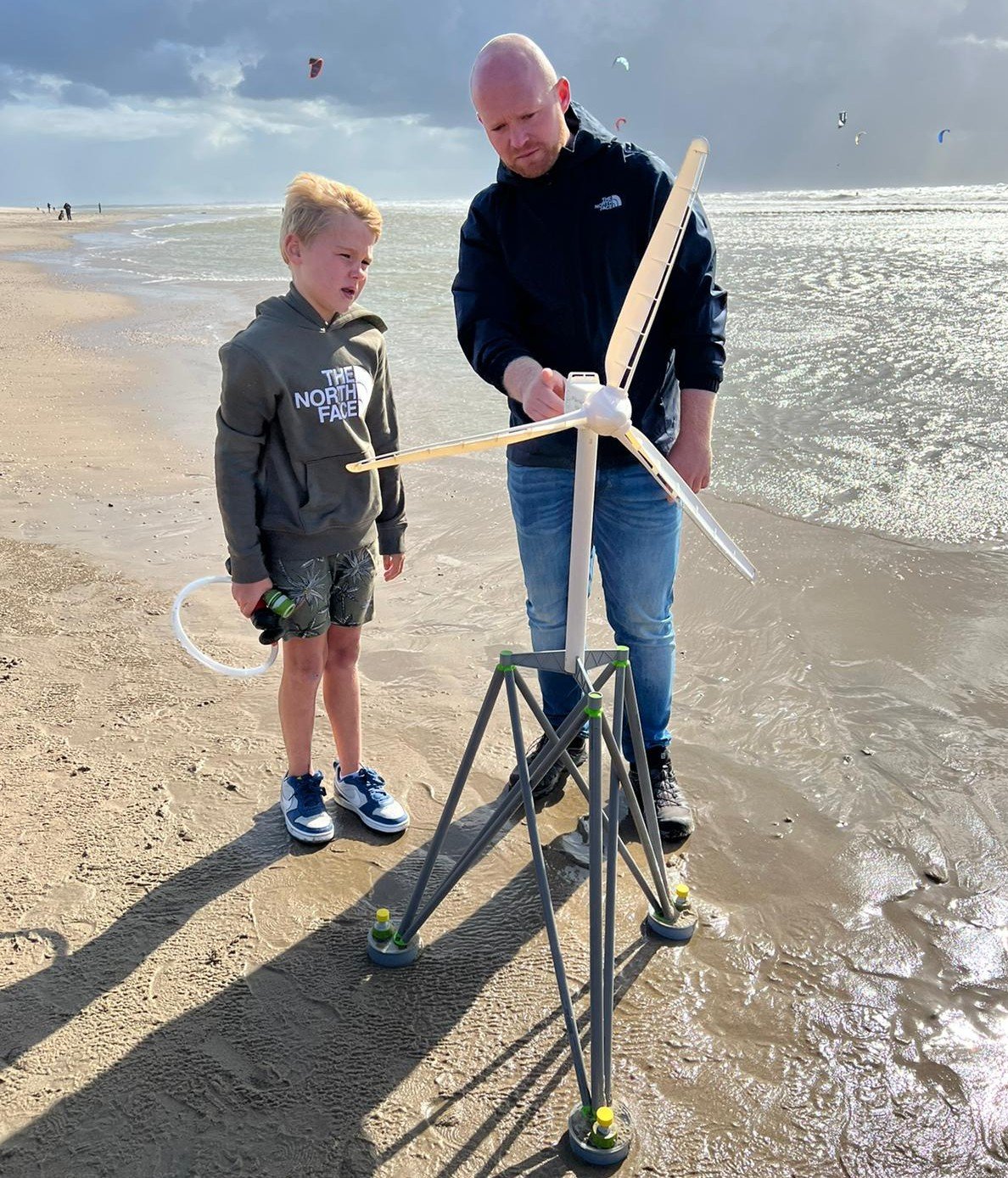 OffshoreWind4Kids workshop participants on a sandy beach assembling a wind turbine model during the renewable energy workshop.