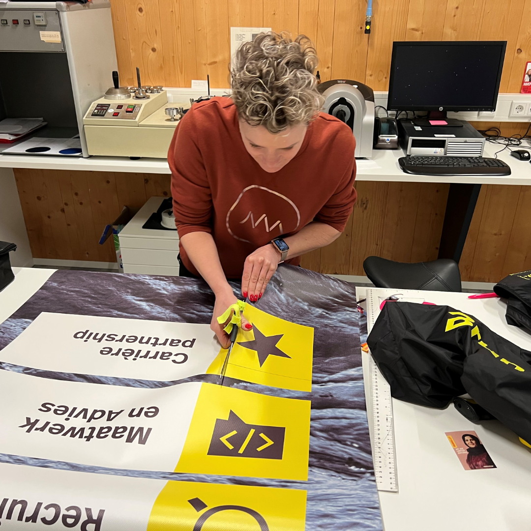 Brunel Foundation Upcycling Workshop Brunel volunteer cutting large printed fabric pieces for an upcycling project in a workshop setting.
