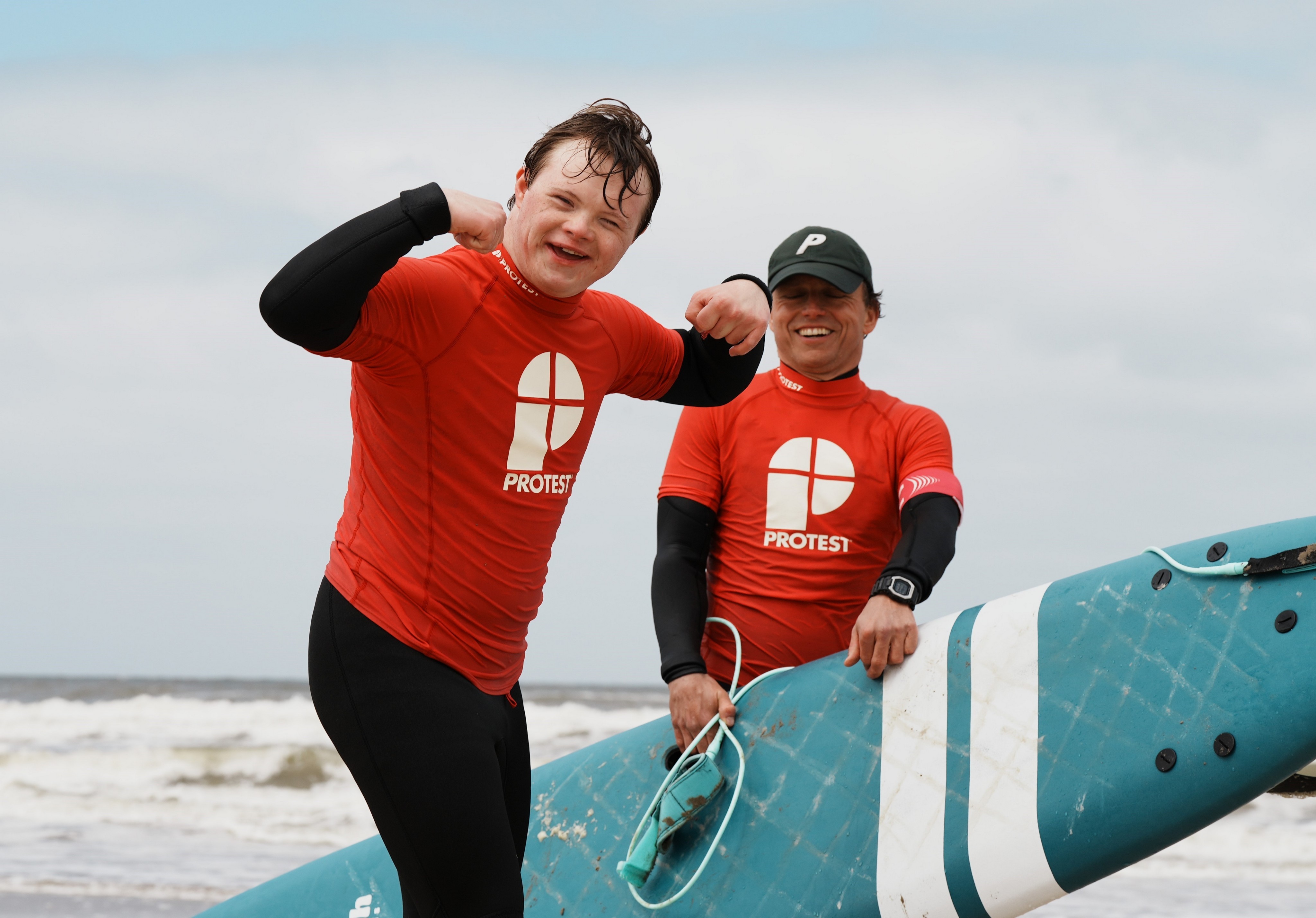 Brunel Foundation Surf Project Two participants in red shirts with a surfboard during a Brunel Foundation surf project event.