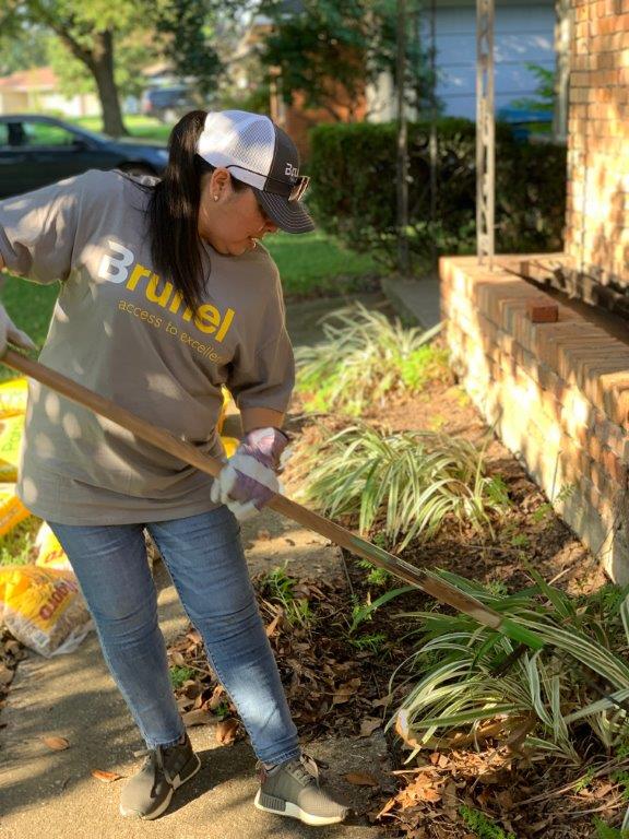 Woman in Brunel shirt and hat maintaining garden