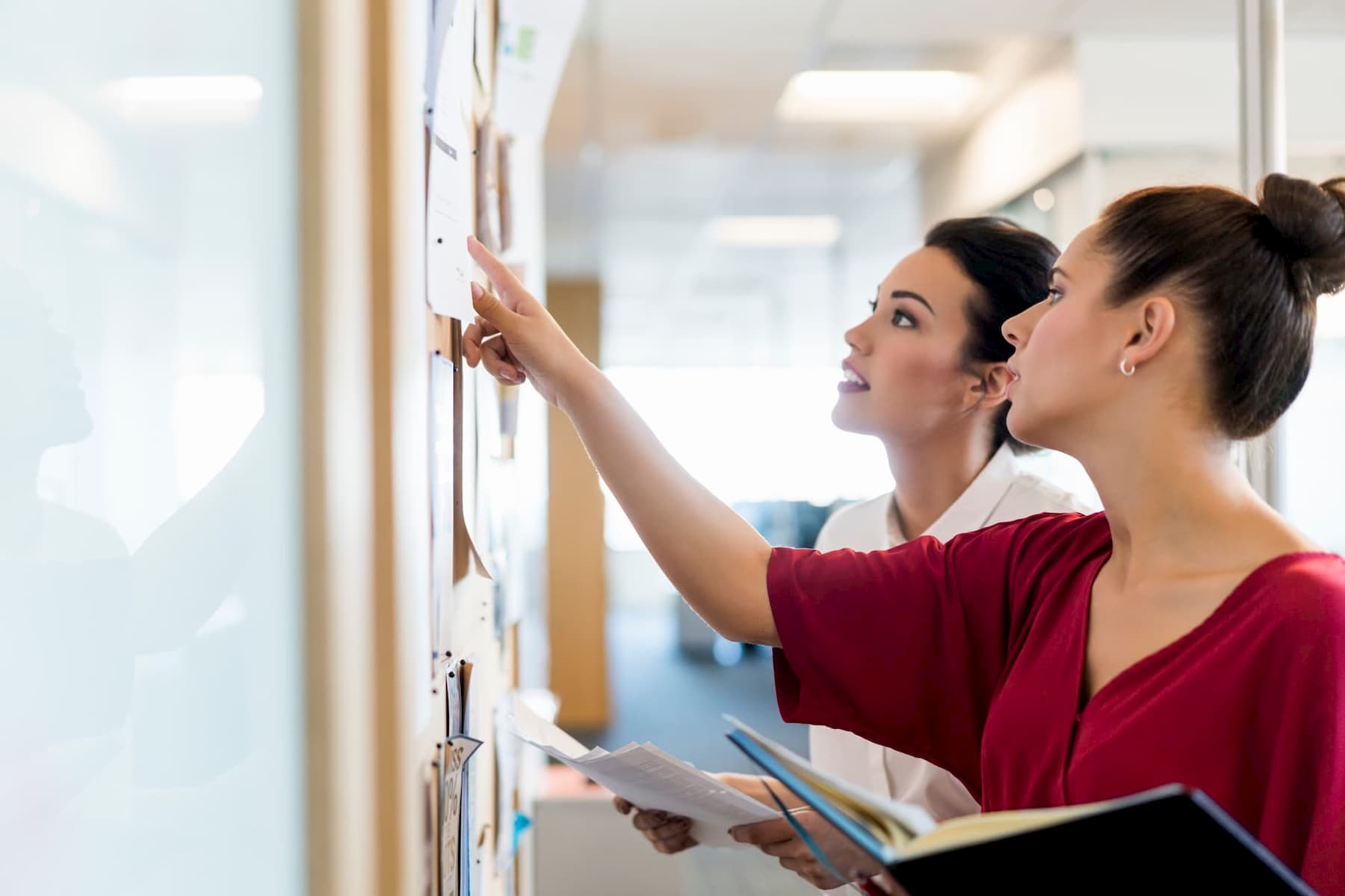 Women attaching advertisement to job board