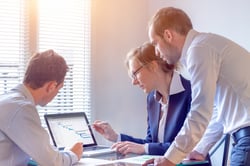 Three people looking at a laptop in an office