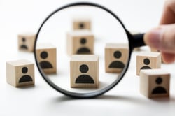 Wooden blocks with a figure behind a magnifying glass