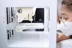 Woman in lab looking at bioprinting machine