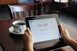 Person holding a tablet with a Google page on it