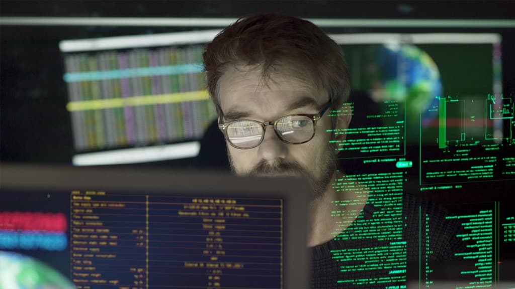 Man behind computer with reflection of data