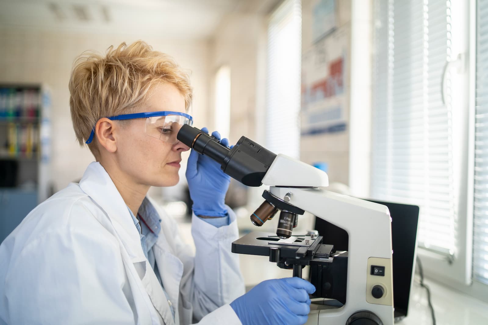Woman looking through a microscope in a lab