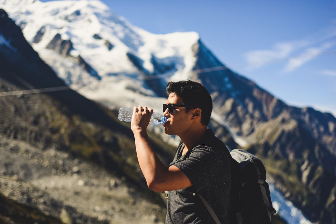 Man drinking from water bottle in mountain landscape