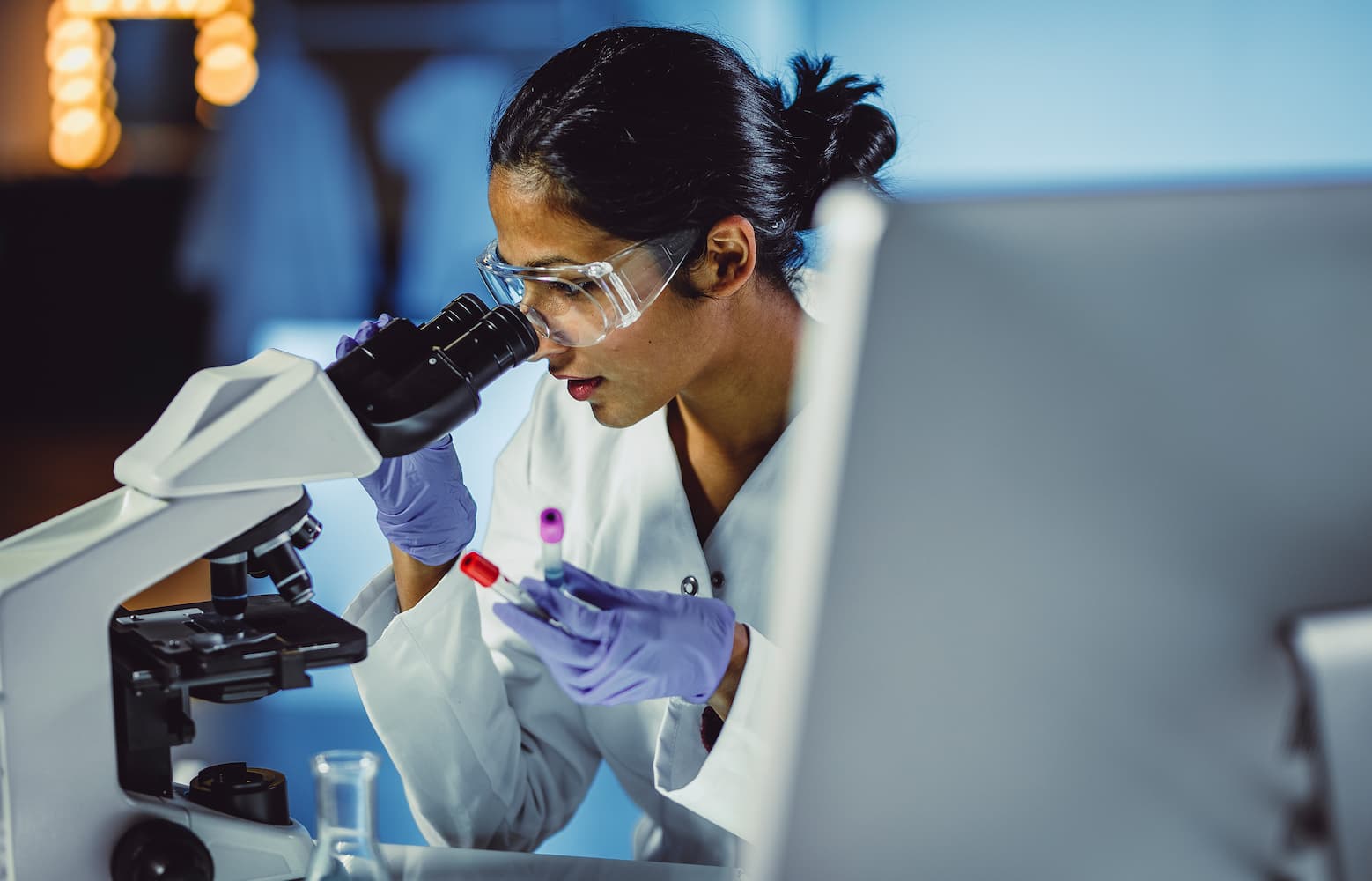 Woman watching a microscope and holding a sample