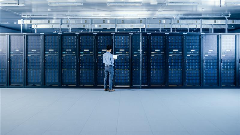 Worker inspecting rows of servers inside a newly constructed data center facility.