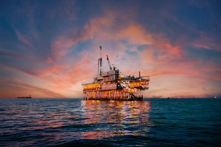 Illuminated offshore oil rig at dusk reflecting on the ocean, highlighting offshore oil drilling jobs and offshore oil rig vacancies