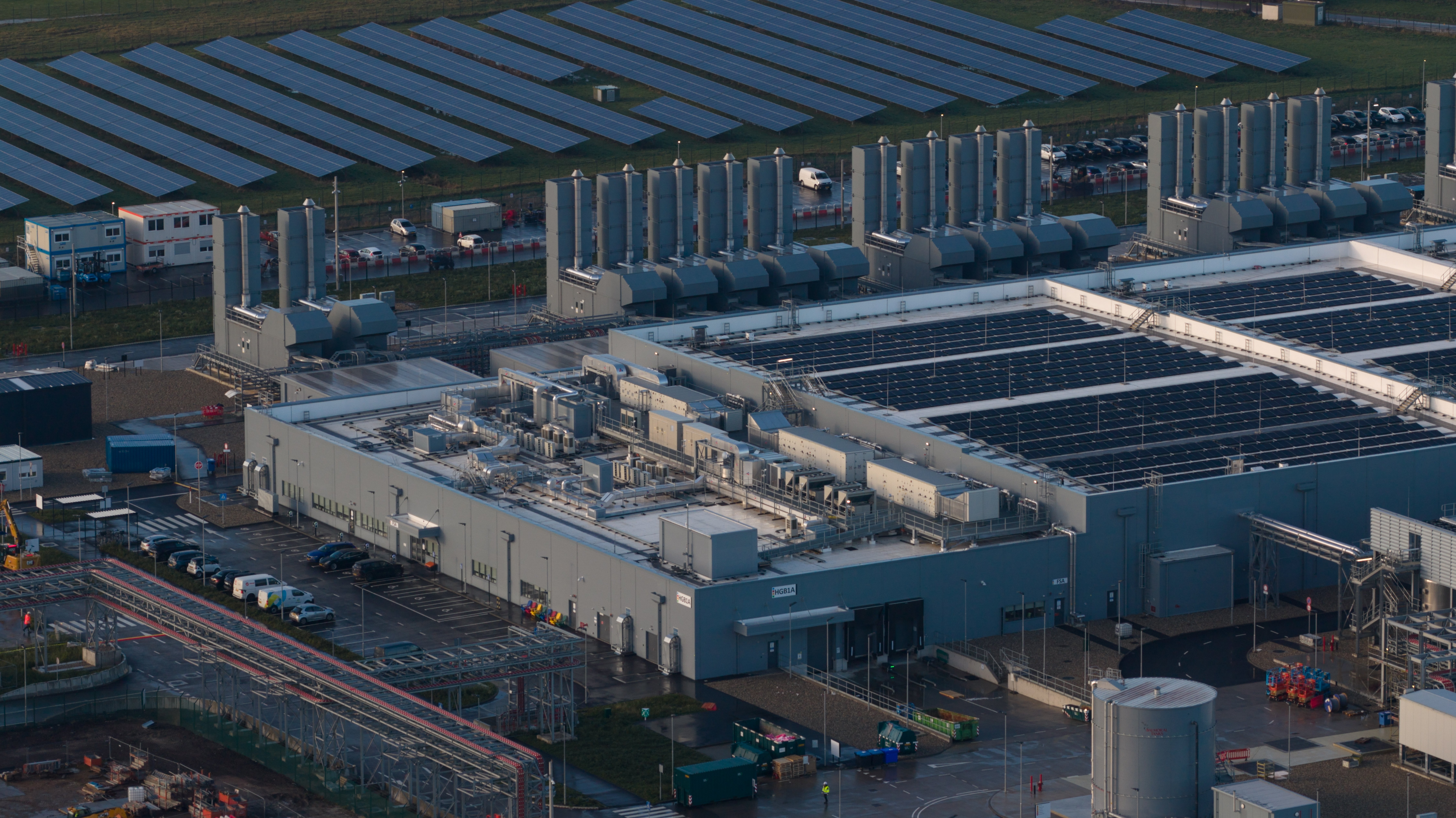Aerial view of a large-scale data center construction site with integrated solar energy infrastructure.