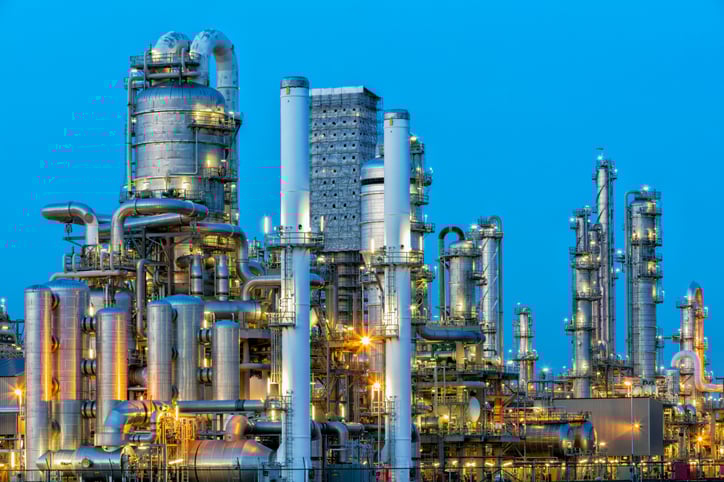 Close view of petrochemical plant towers and pipelines at blue hour—processing facilities connected to oil rig jobs