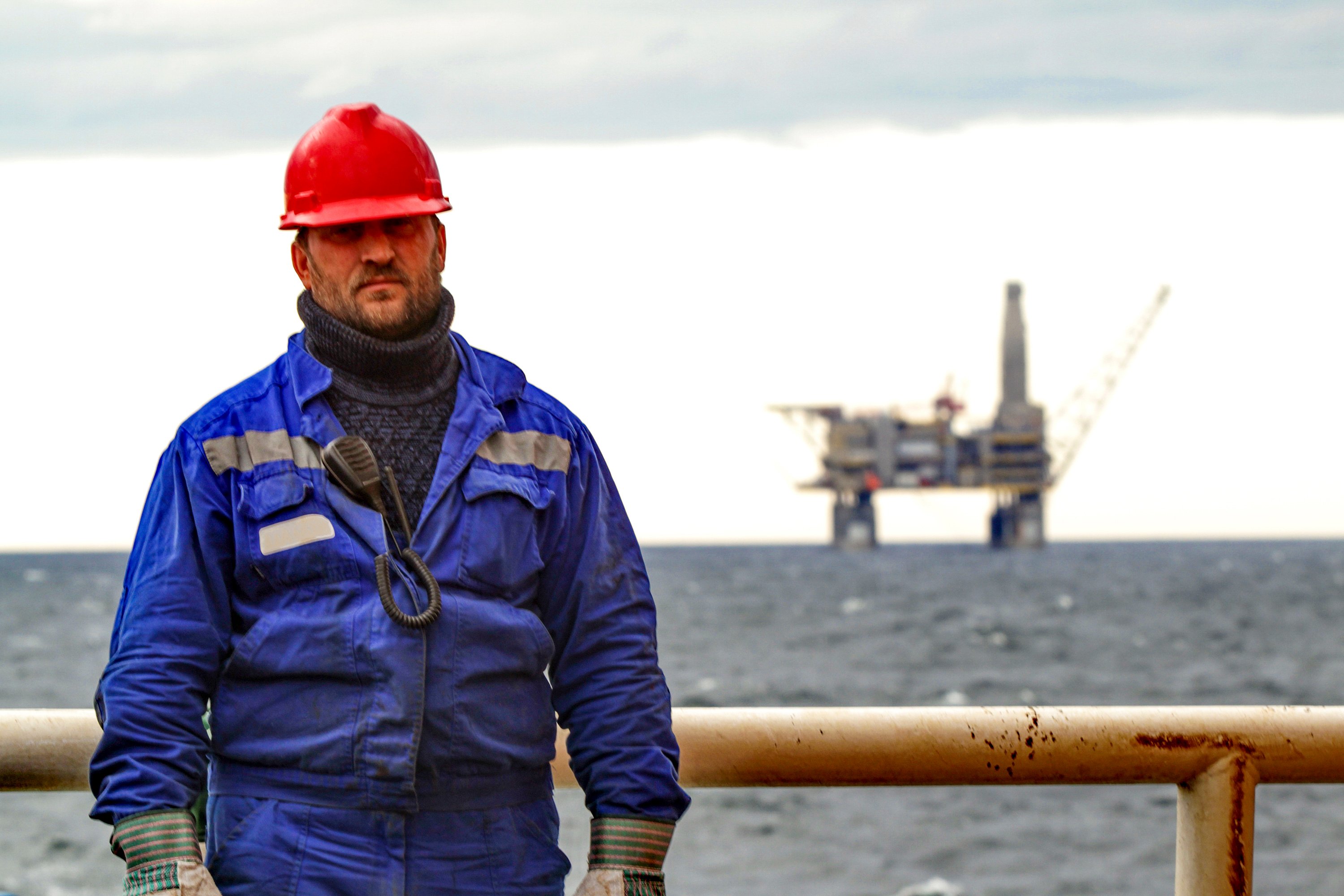 Offshore oil platform worker standing on a rig with drilling operations offshore