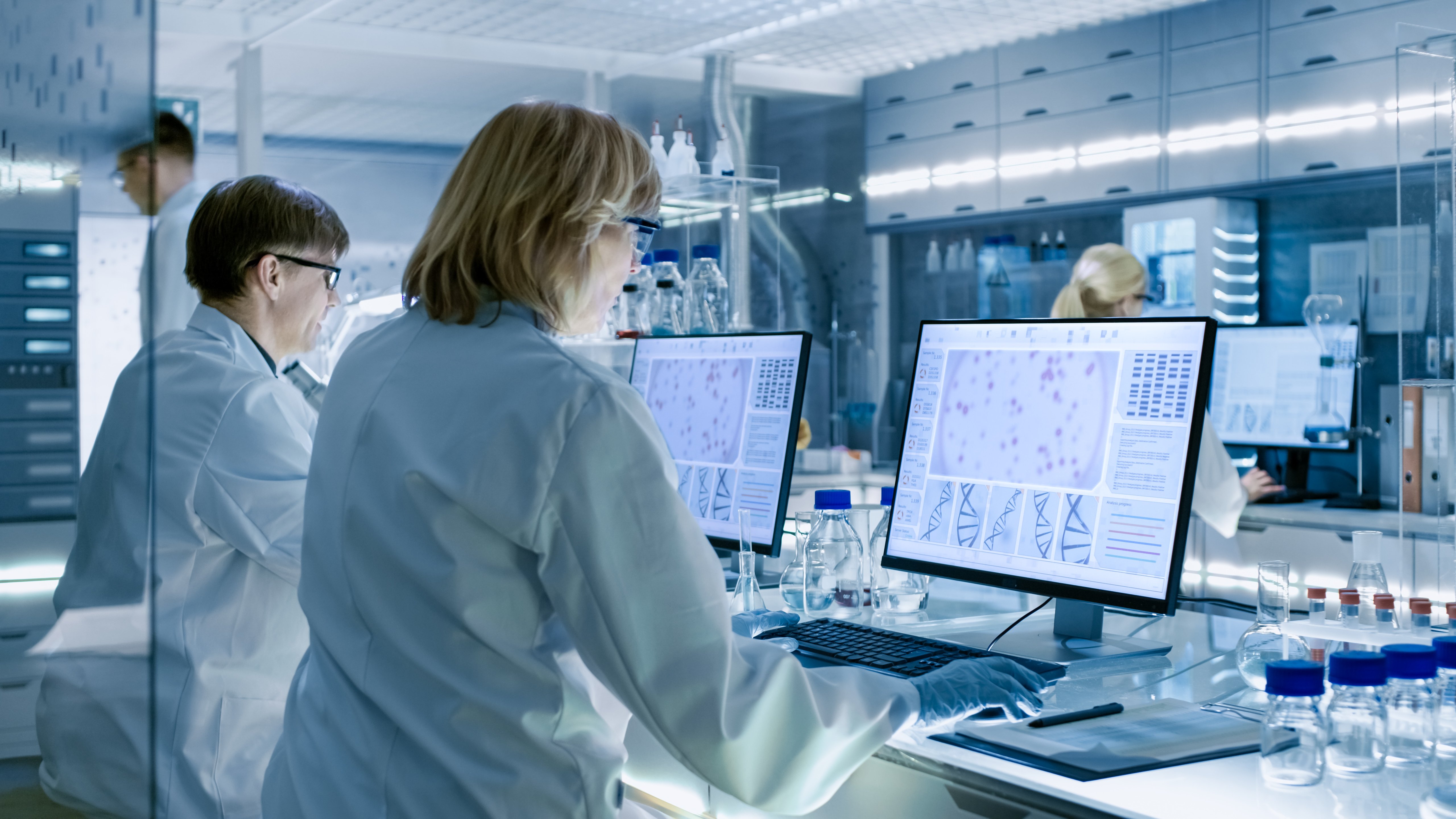 Group of scientists analyzing research findings on computer monitors in a modern laboratory setting, illustrating teamwork in medical science liaison roles.