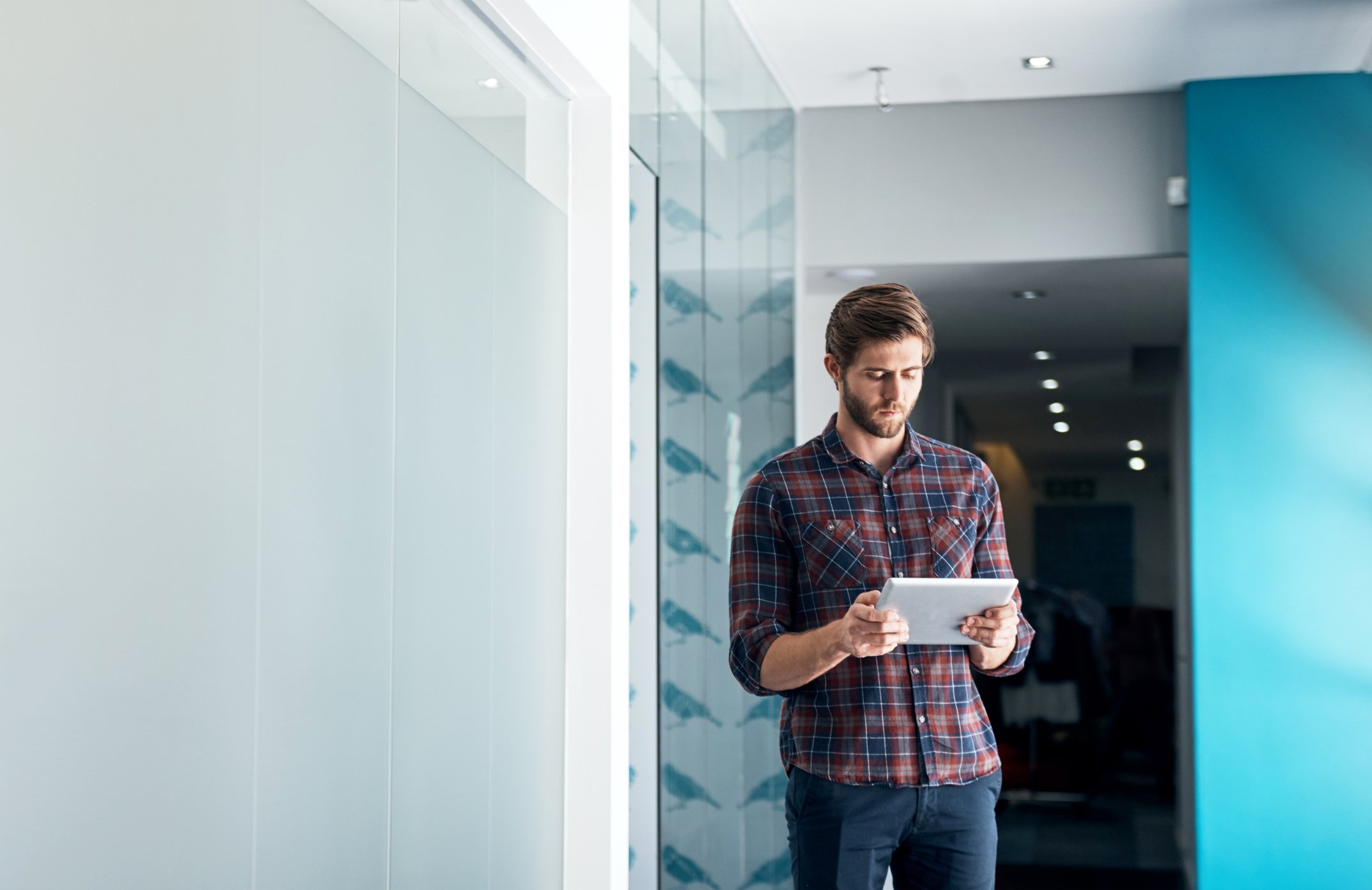 Company founder looks down at tablet in an office. he and many like him wonder 'is my company too small for an RPO'