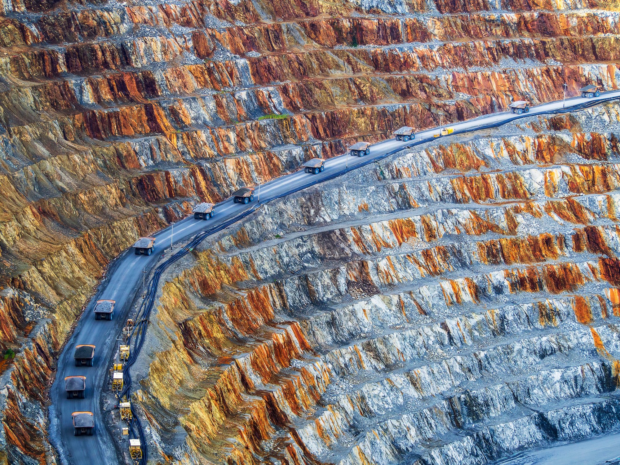 Mining trucks drive up a mine to show growth seen in the mining market