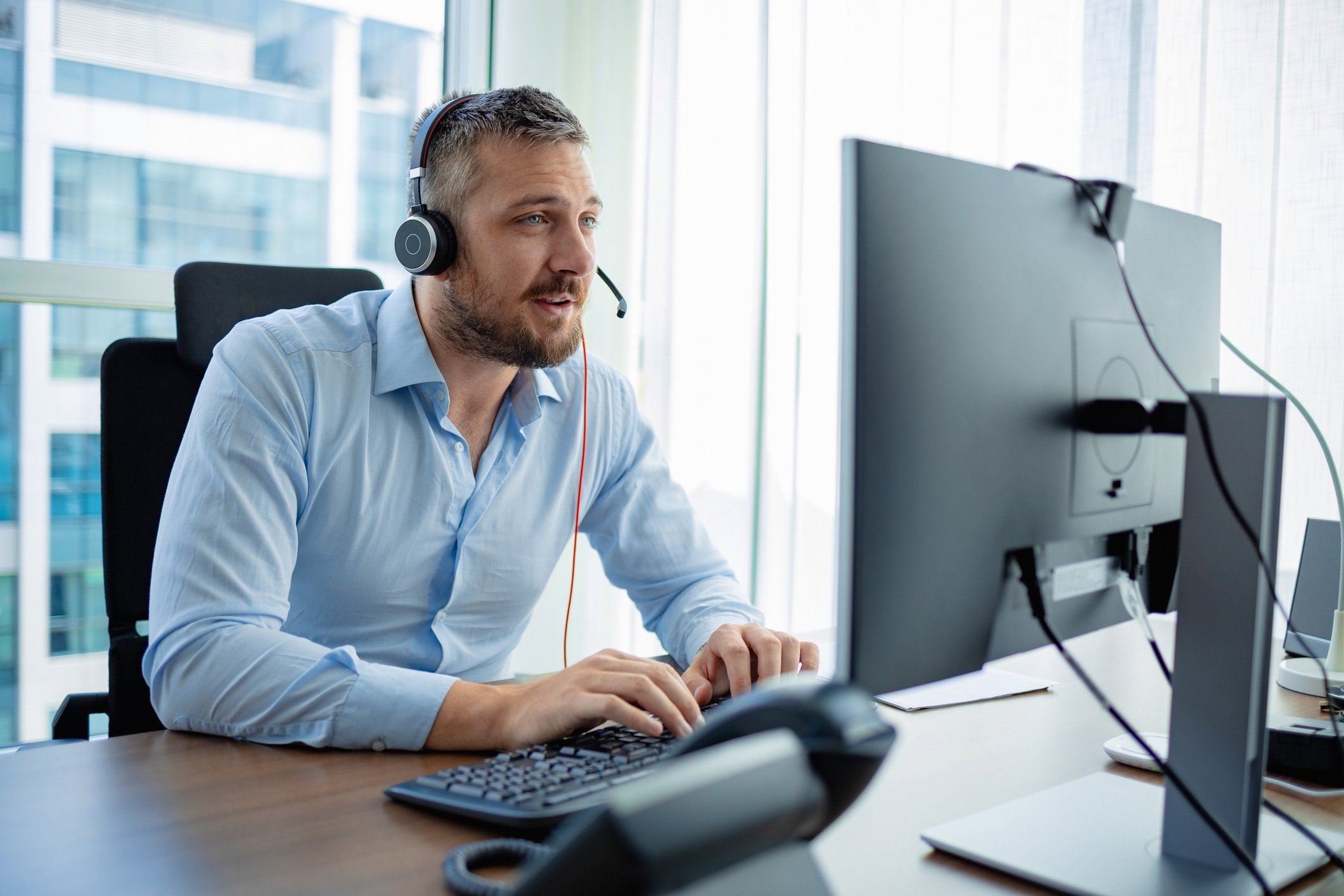 Recruitment consultant with headset at desk